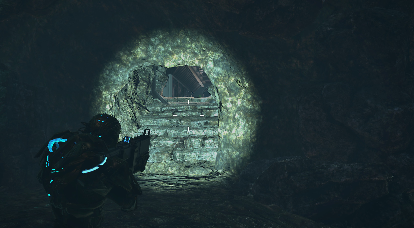 An armored character explores a dark stone tunnel illuminated by a weapon light.